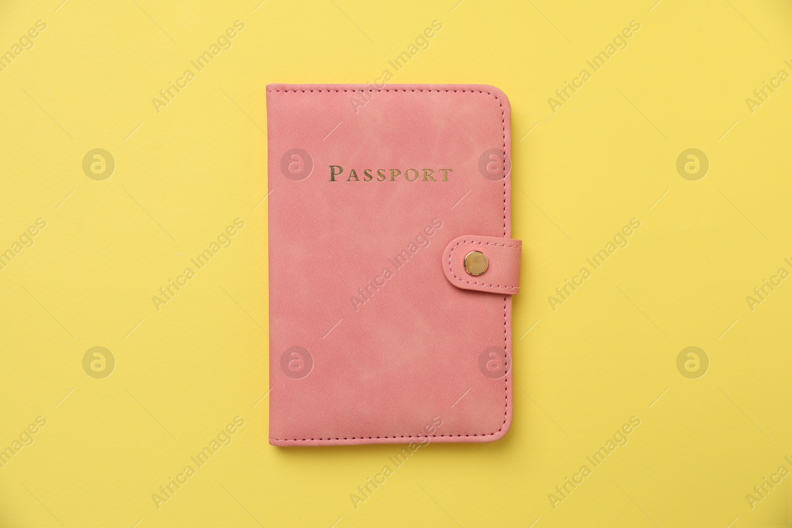 Photo of Passport in bright cover on yellow background, top view