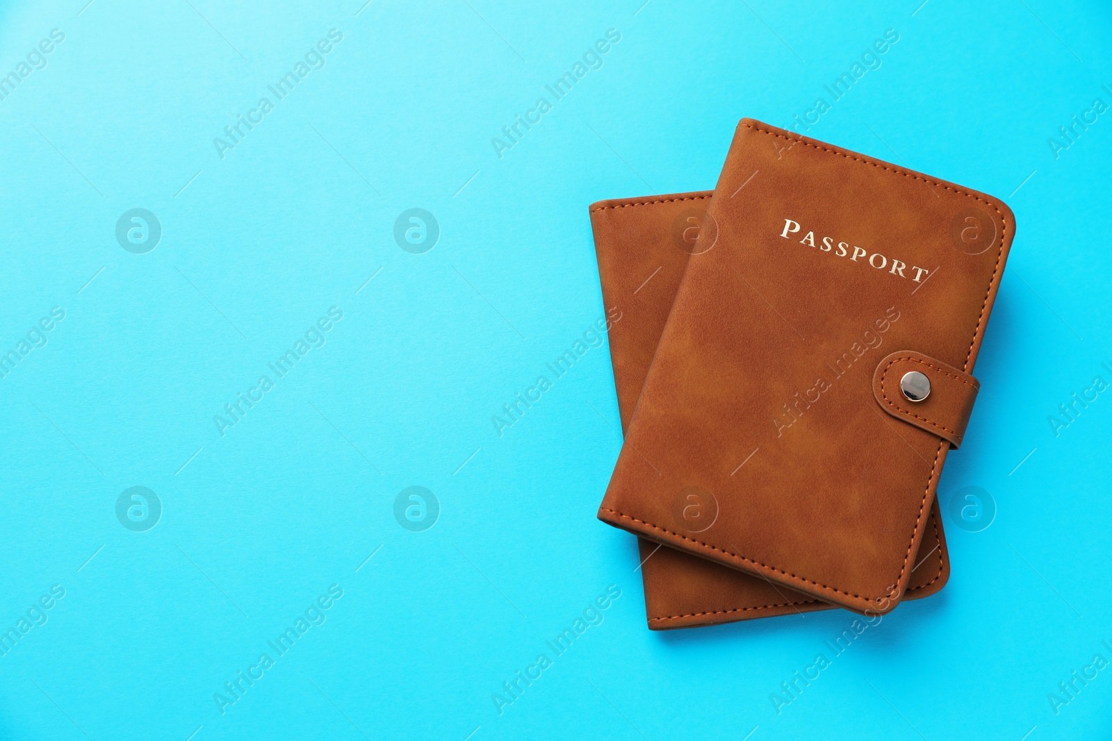 Photo of Passports in brown covers on light blue background, top view. Space for text