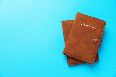 Photo of Passports in brown covers on light blue background, top view. Space for text