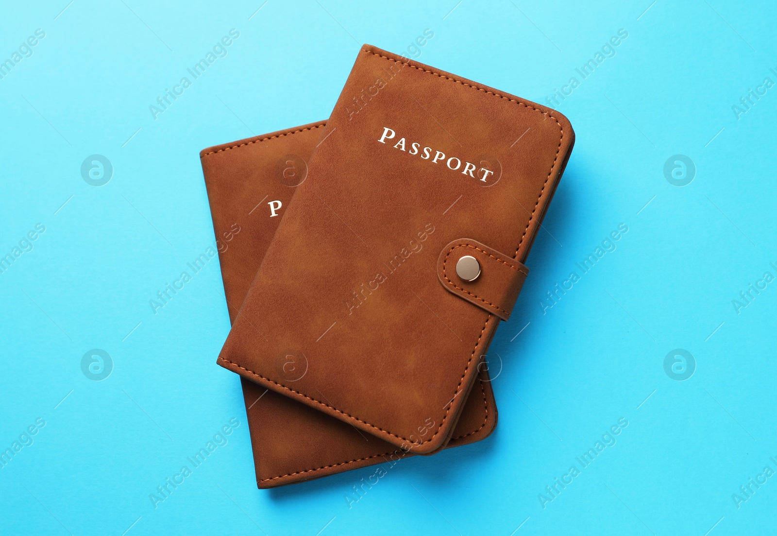 Photo of Passports in brown covers on light blue background, top view