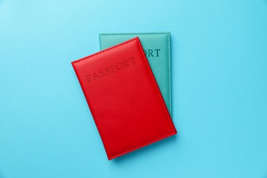 Photo of Passports in color covers on light blue background, top view