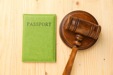 Photo of Passport in green cover and judge's gavel on wooden table, top view