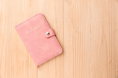 Photo of Passport in pink cover on wooden table, top view. Space for text