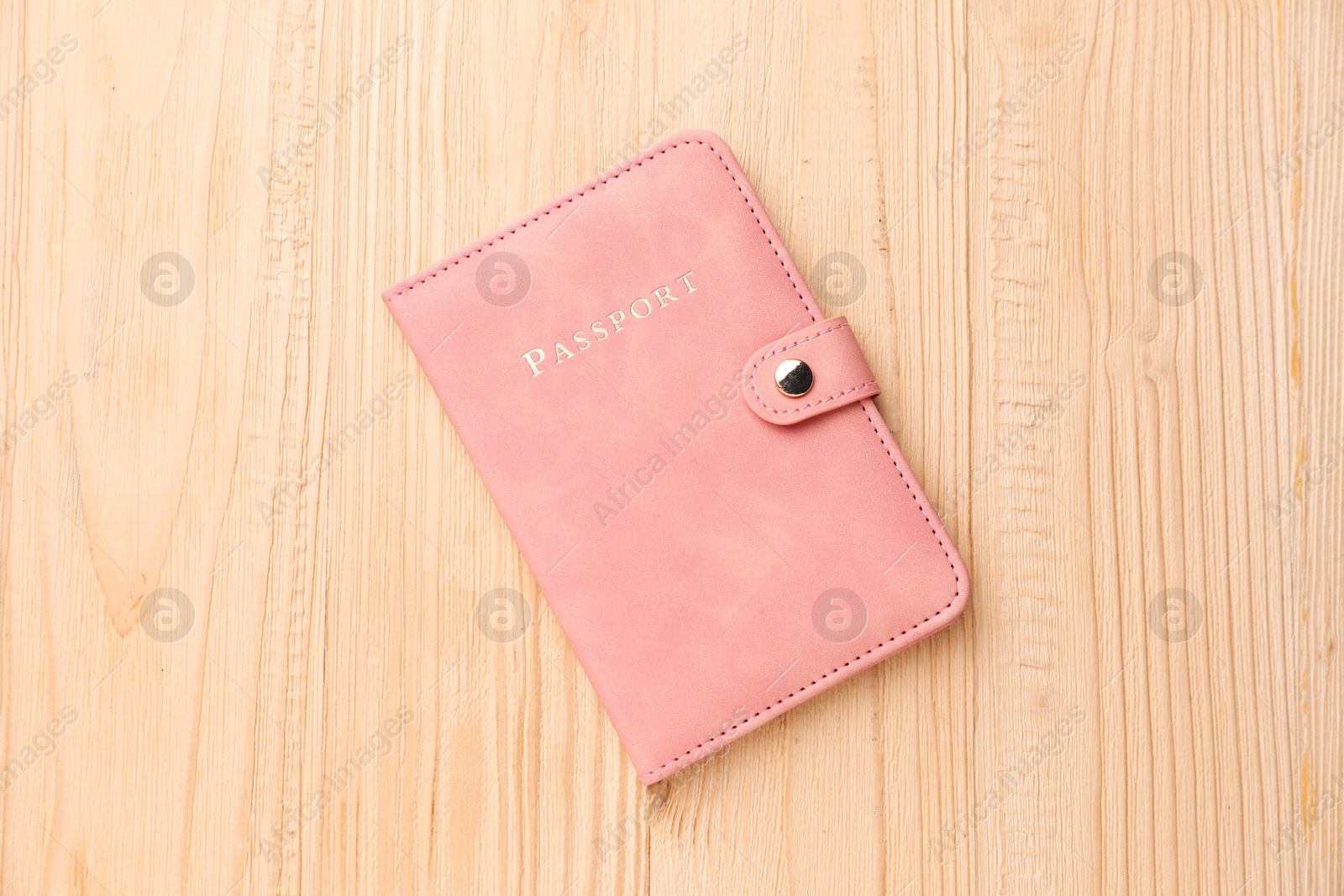 Photo of Passport in pink cover on wooden table, top view