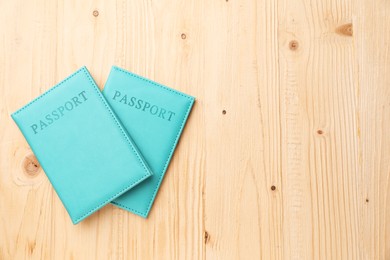 Photo of Passports in light blue covers on wooden table, top view. Space for text