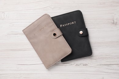 Photo of Passports in color covers on light wooden table, top view