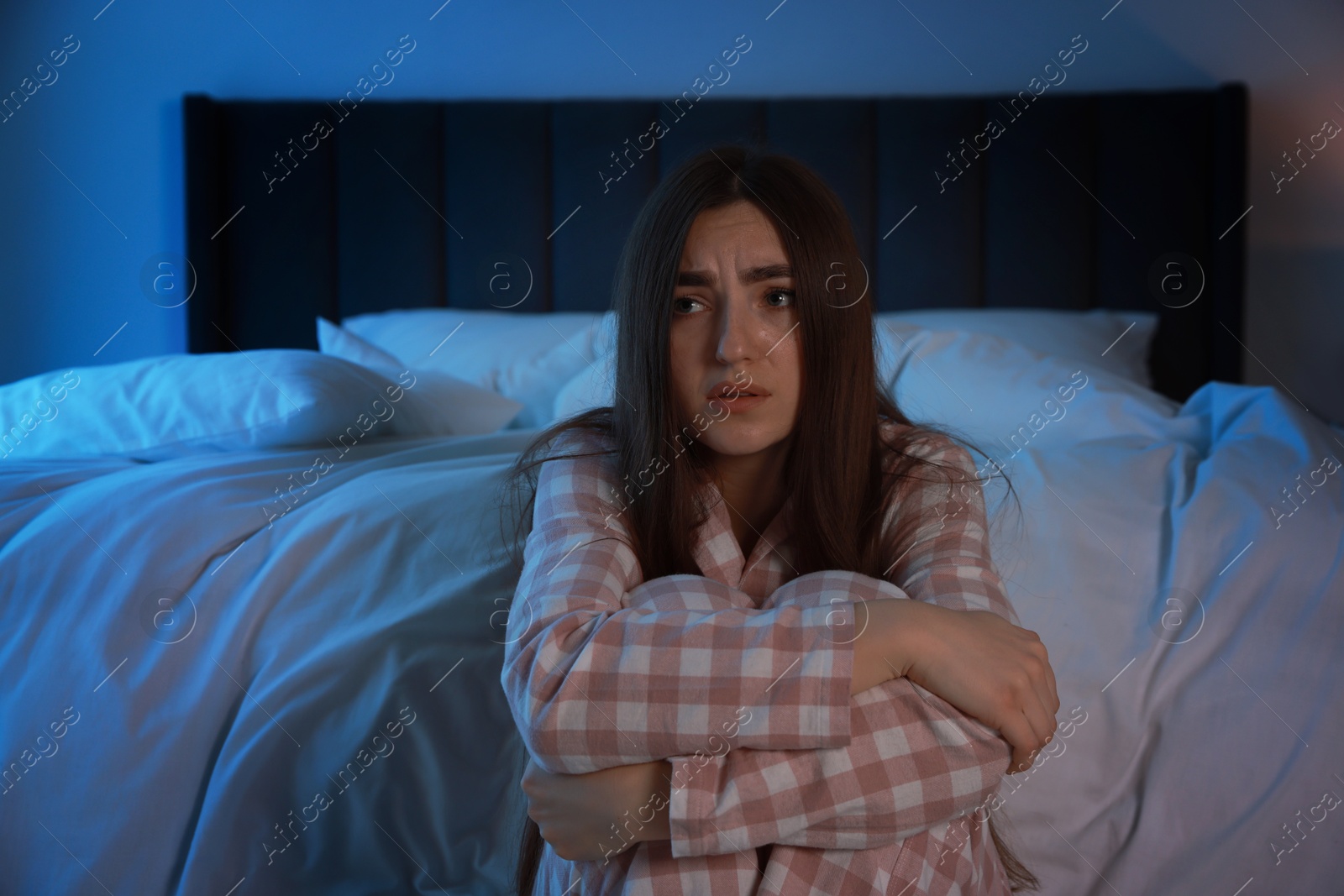 Photo of Fear of darkness. Scared young woman in bedroom at night