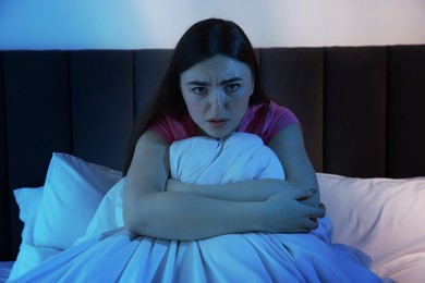 Photo of Fear of darkness. Scared young woman on bed in room at night