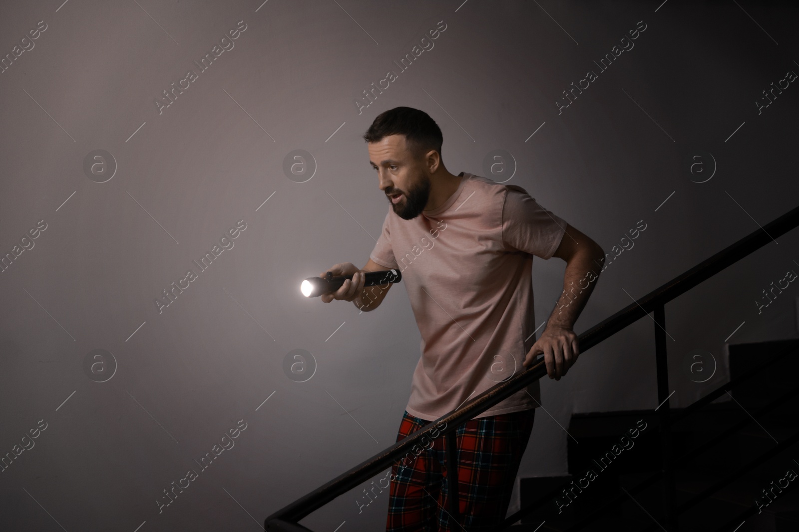 Photo of Fear of darkness. Scared man with flashlight indoors at night