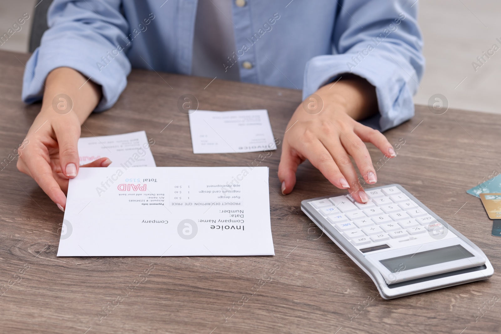 Photo of Paying bills. Woman with different invoices and calculator at wooden table indoors, closeup