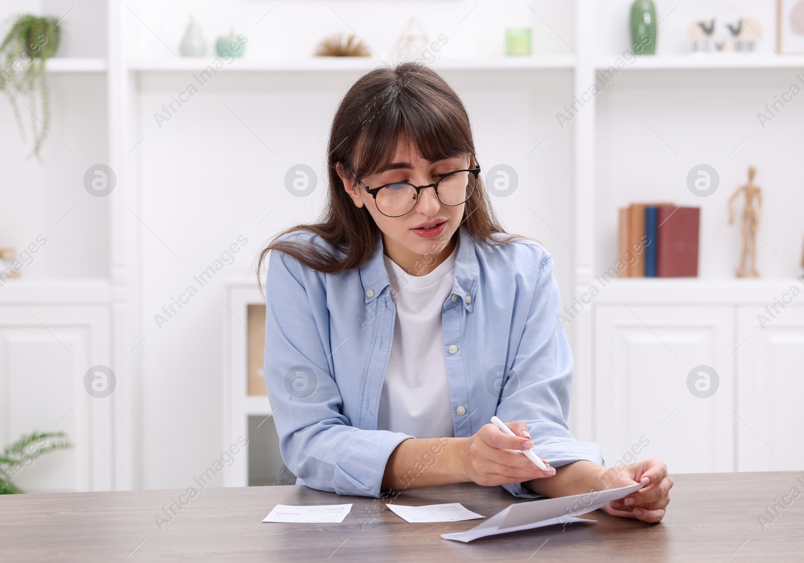 Photo of Paying bills. Woman with different invoices at wooden table indoors