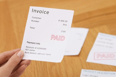 Photo of Paying bills. Woman with different invoices at wooden table indoors, closeup