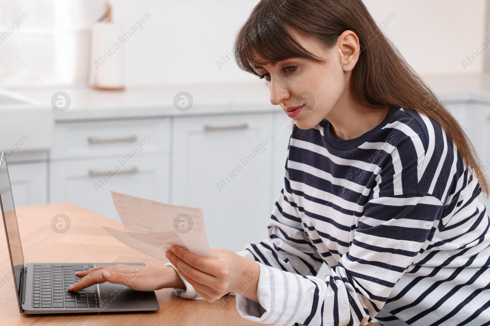 Photo of Paying bills. Woman with different invoices and laptop at wooden table indoors