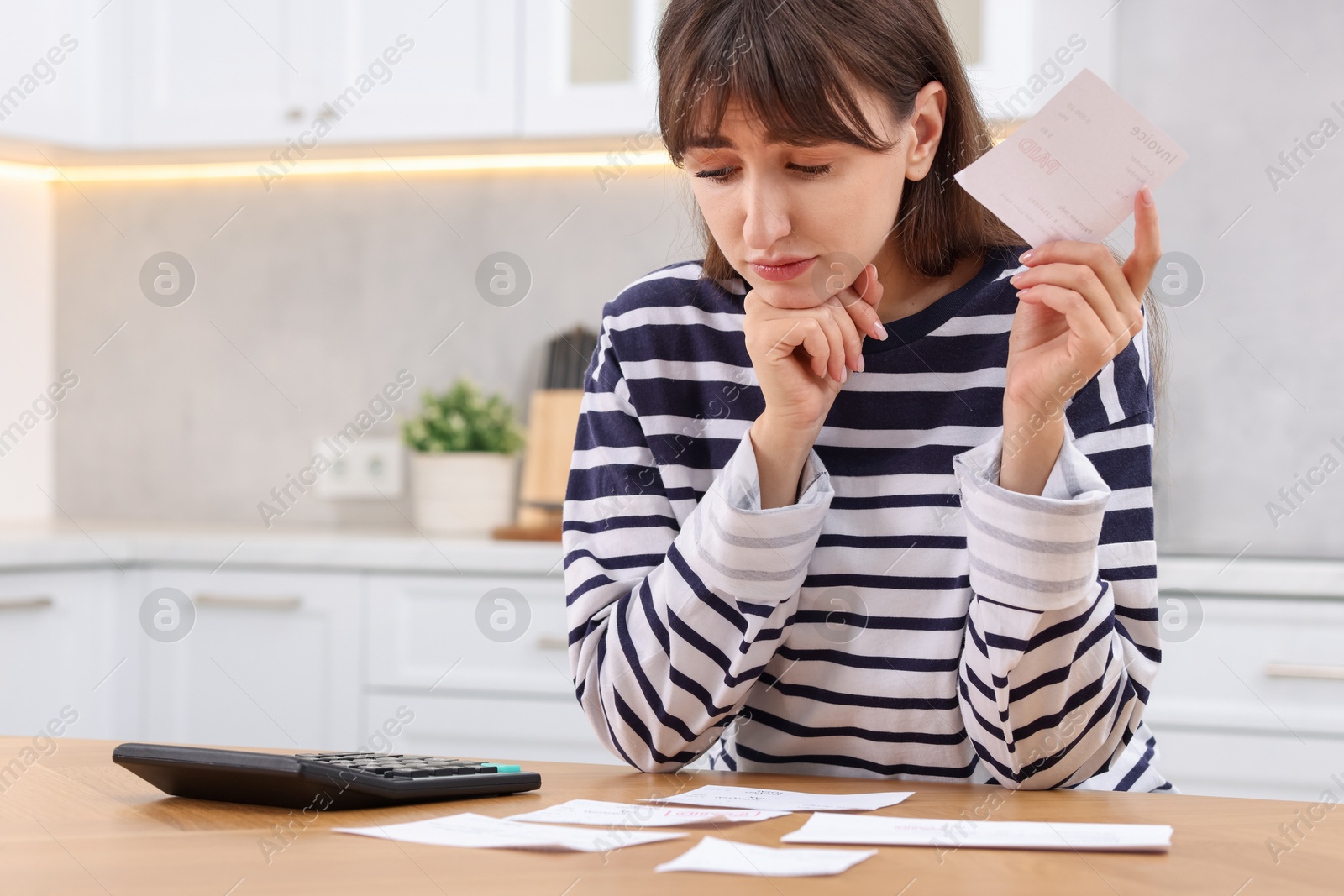 Photo of Paying bills. Woman with different invoices and calculator at wooden table indoors