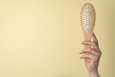 Photo of Woman with wooden brush on beige background, closeup. Space for text