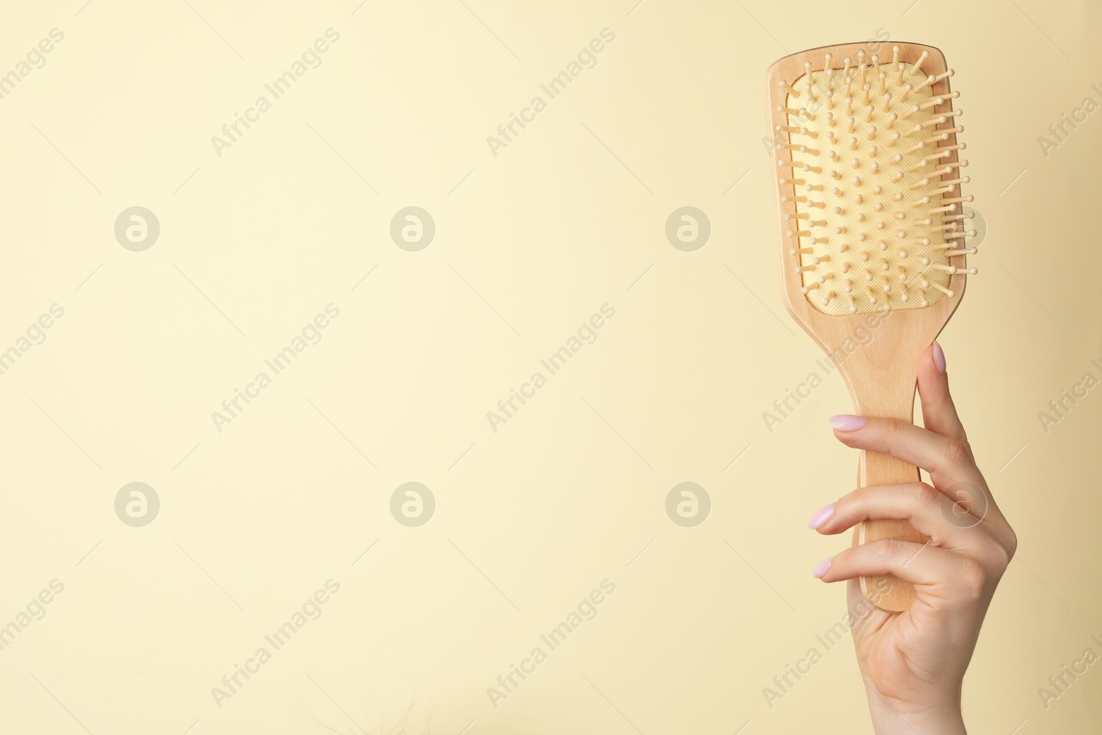 Photo of Woman with wooden brush on beige background, closeup. Space for text