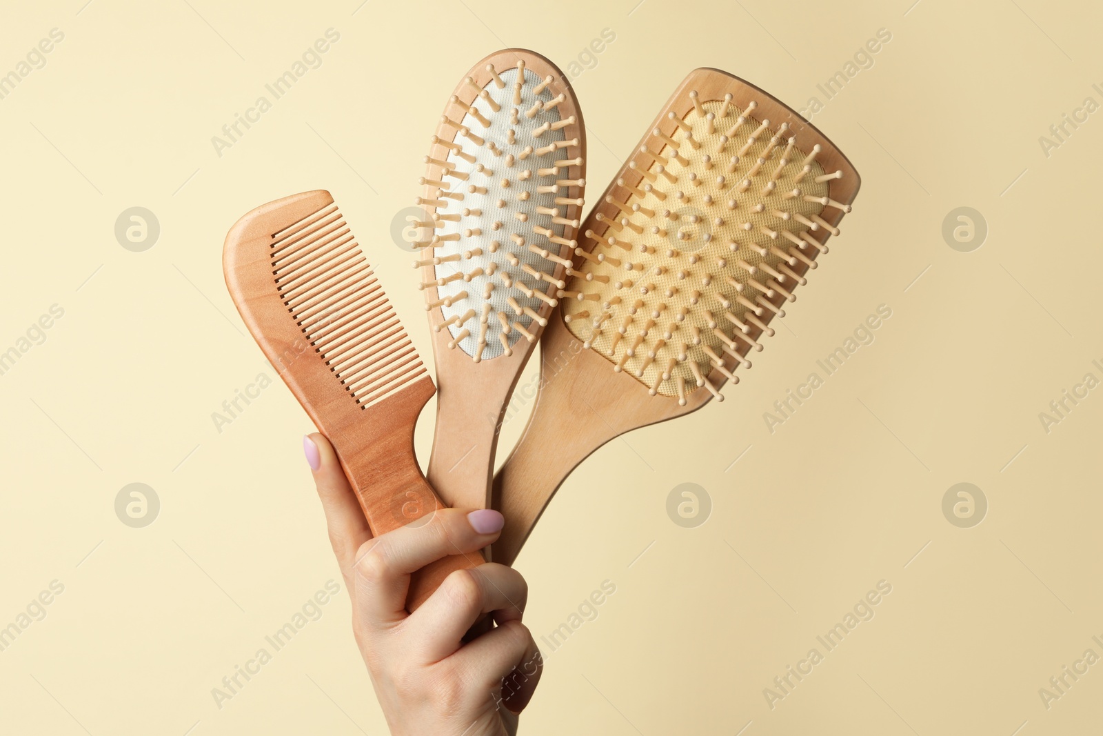 Photo of Woman with wooden brushes and comb on beige background, closeup