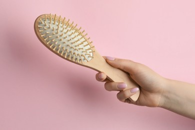 Photo of Woman with wooden brush on pink background, closeup