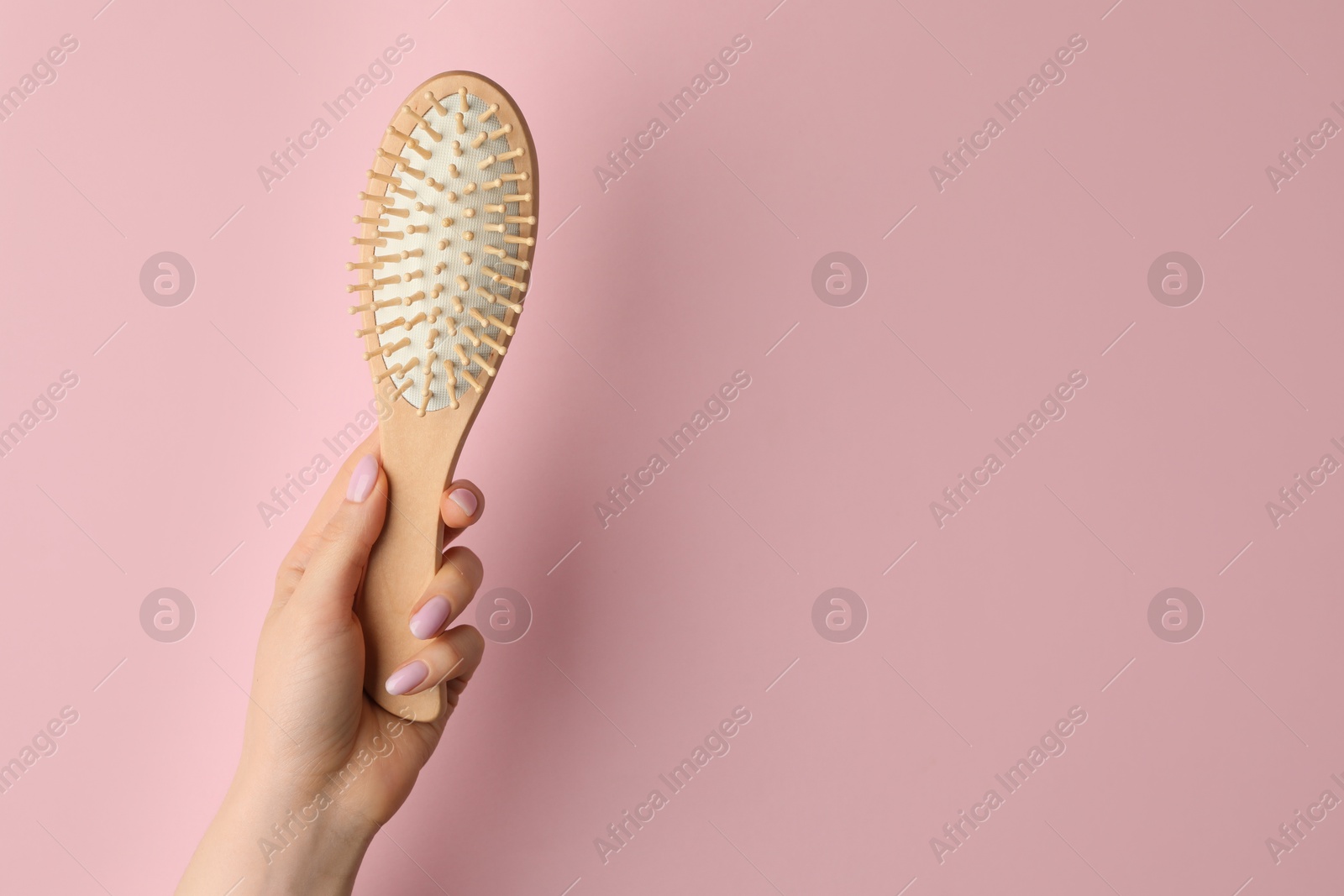 Photo of Woman with wooden brush on pink background, closeup. Space for text