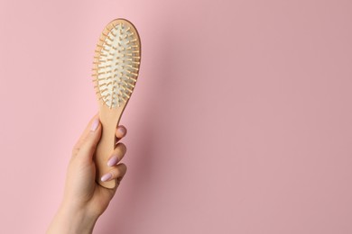 Photo of Woman with wooden brush on pink background, closeup. Space for text