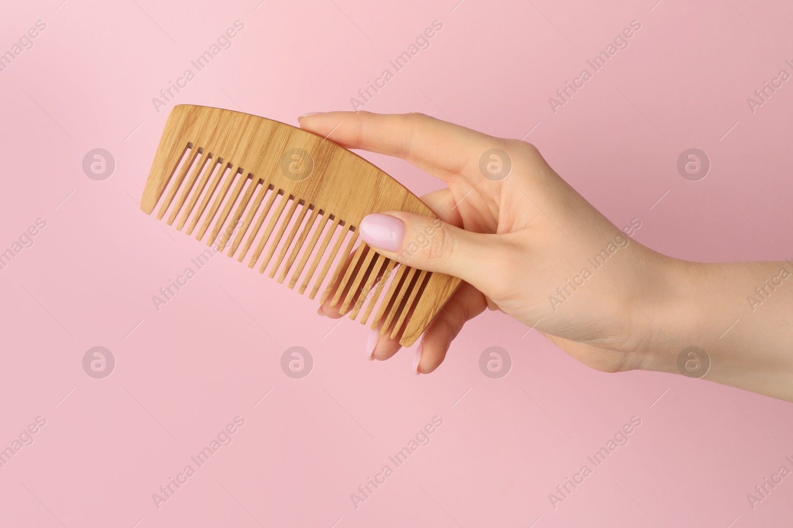 Photo of Woman with wooden comb on pink background, closeup. Space for text