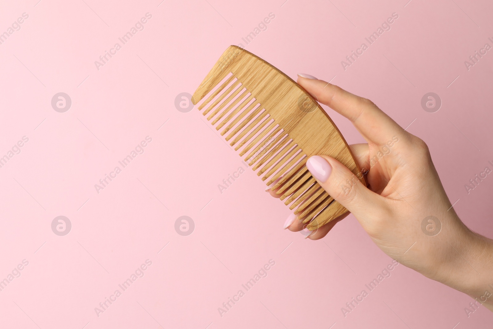 Photo of Woman with wooden comb on pink background, closeup. Space for text