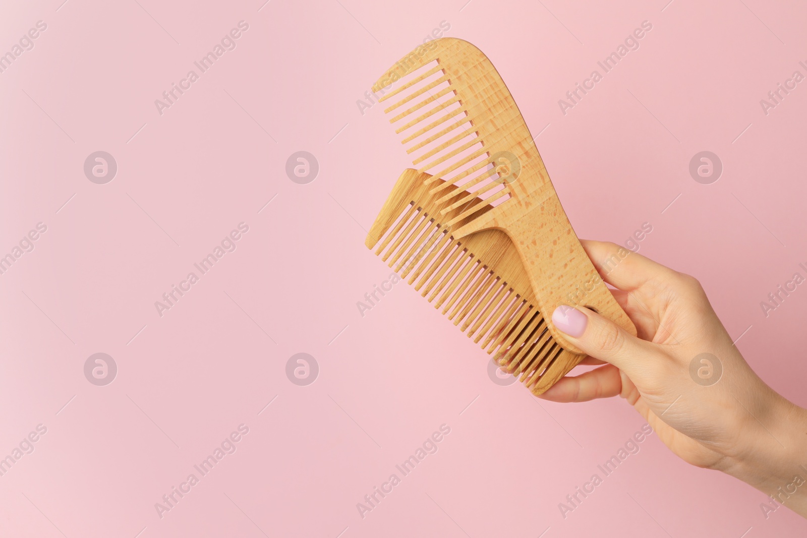 Photo of Woman with wooden combs on pink background, closeup. Space for text