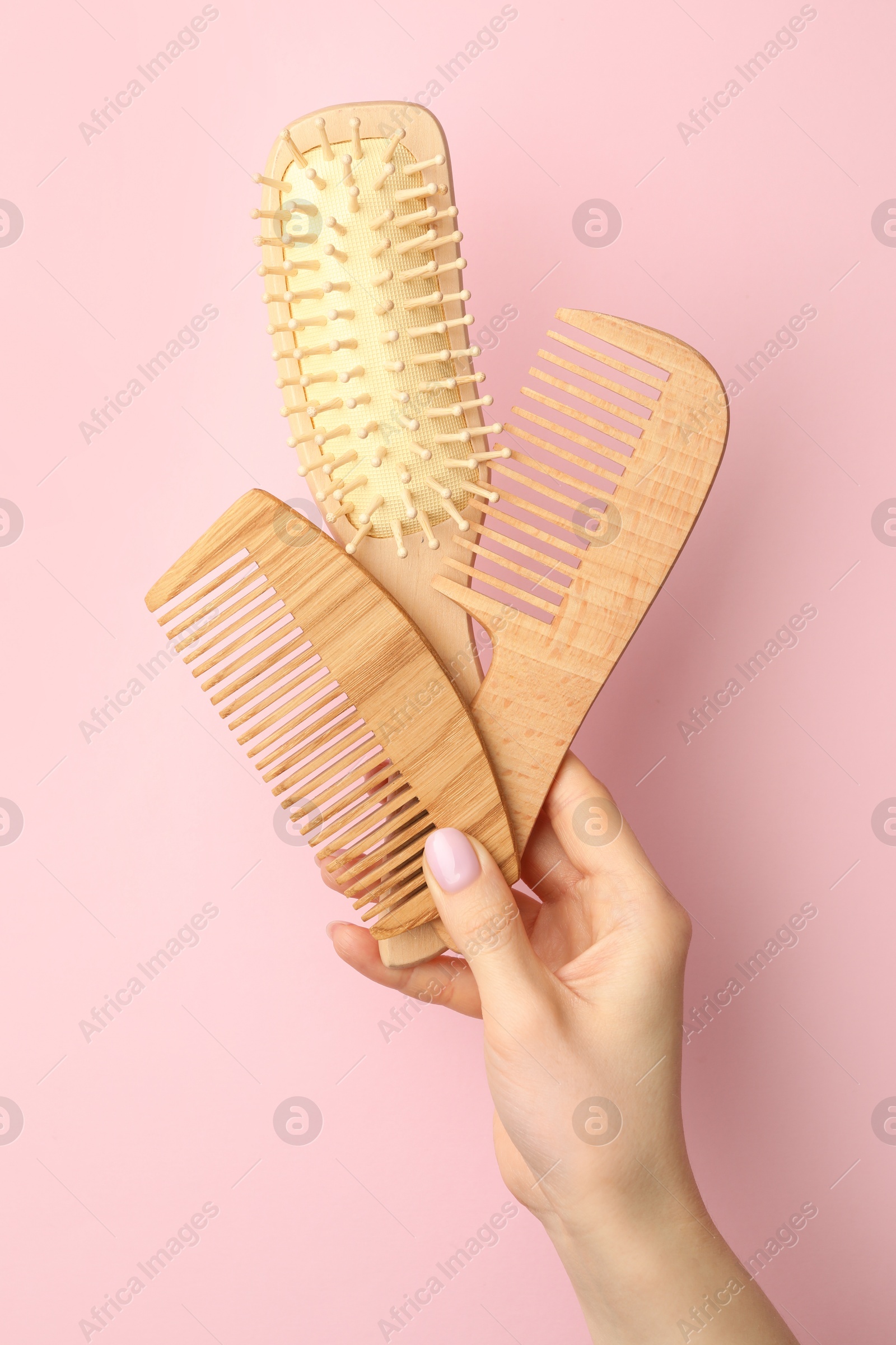 Photo of Woman with wooden brush and combs on pink background, closeup