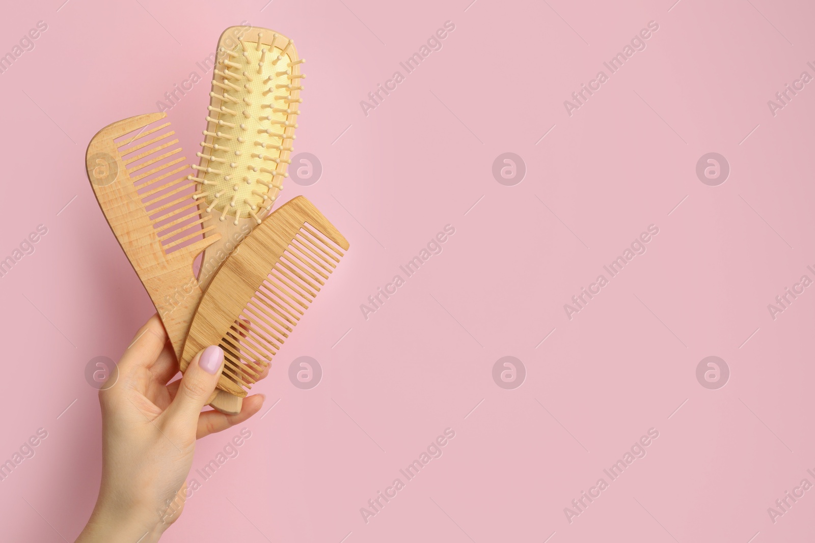 Photo of Woman with wooden brush and combs on pink background, closeup. Space for text