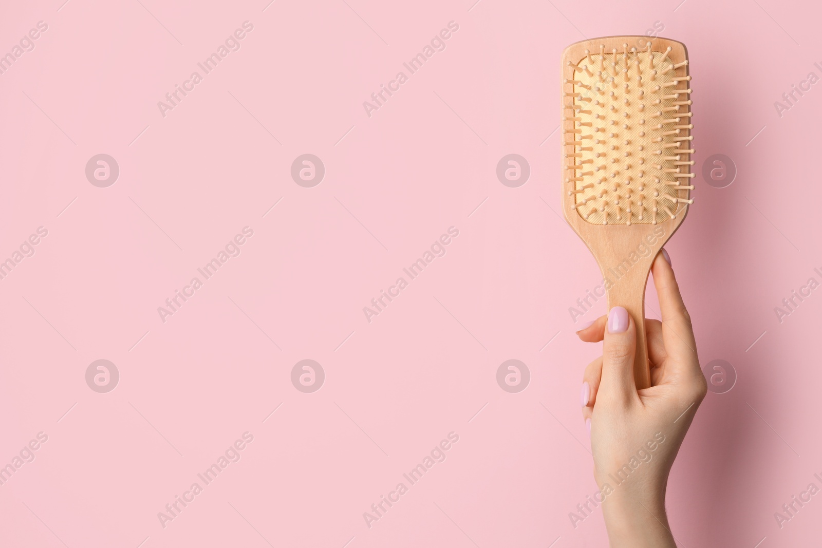 Photo of Woman with wooden brush on pink background, closeup. Space for text