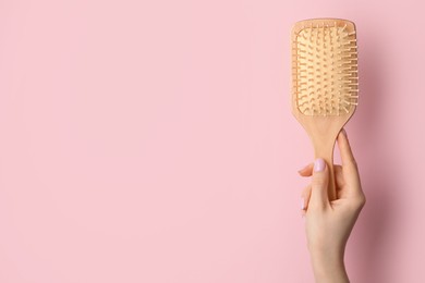 Photo of Woman with wooden brush on pink background, closeup. Space for text