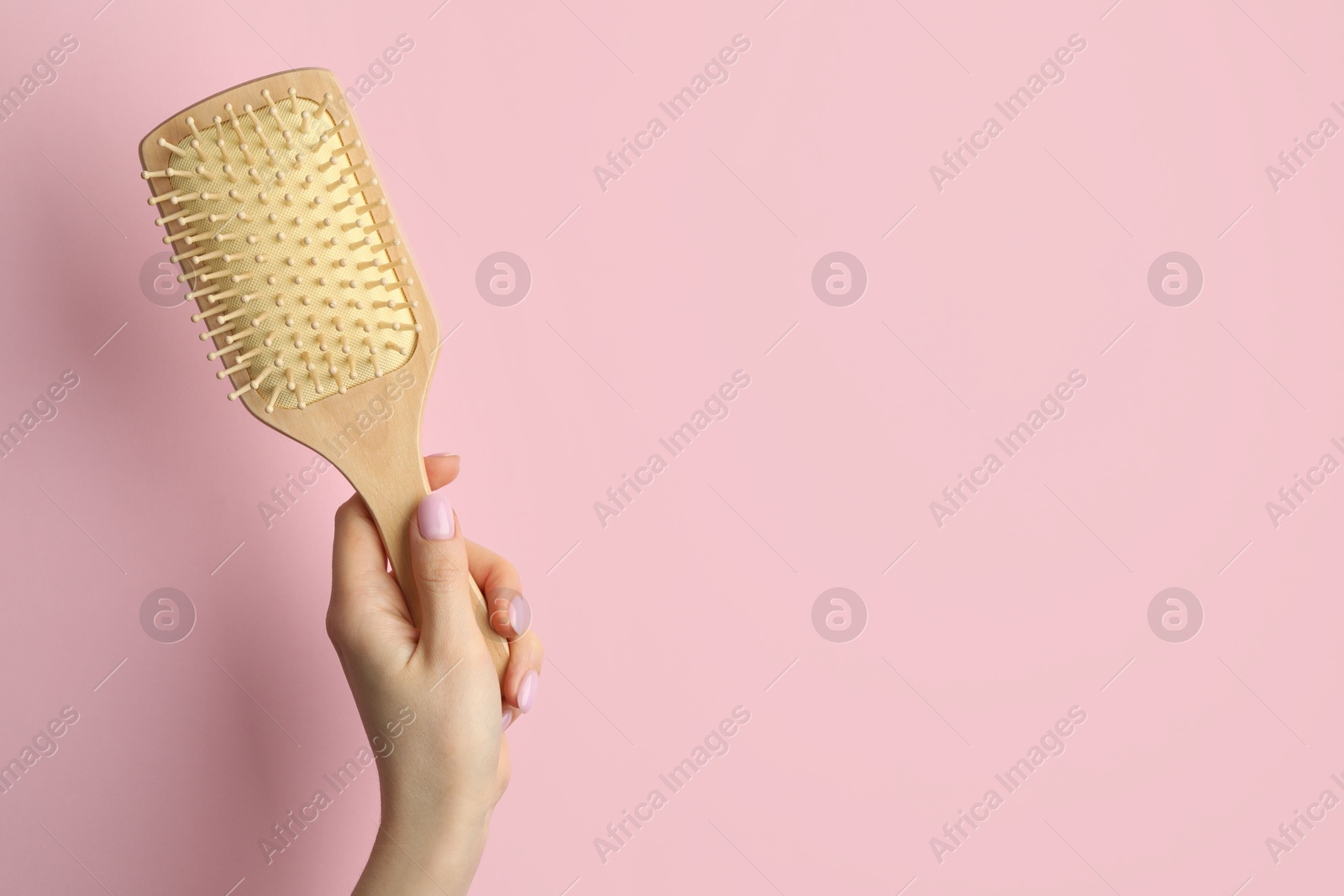 Photo of Woman with wooden brush on pink background, closeup. Space for text