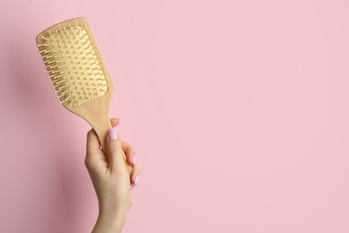 Photo of Woman with wooden brush on pink background, closeup. Space for text