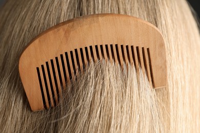 Photo of Brushing hair with wooden comb, closeup view