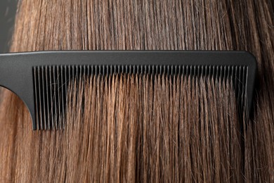 Photo of Brushing hair with plastic comb, closeup view