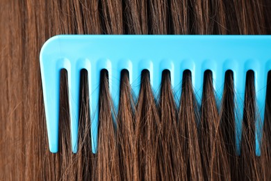 Photo of Brushing hair with plastic comb, closeup view