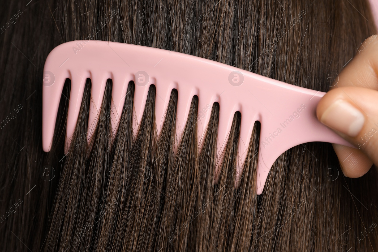 Photo of Woman brushing hair with plastic comb, closeup