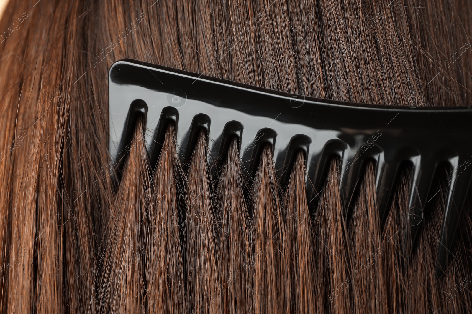 Photo of Brushing hair with plastic comb, closeup view