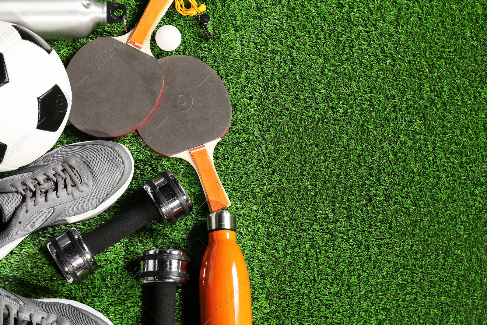 Photo of Different sports equipment on artificial grass, flat lay. Space for text