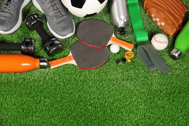 Photo of Different sports equipment on artificial grass, flat lay. Space for text