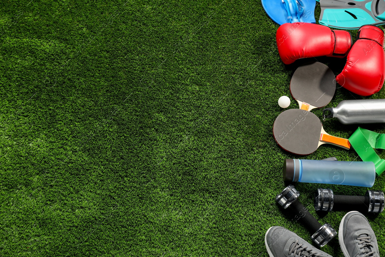 Photo of Different sports equipment on artificial grass, flat lay. Space for text