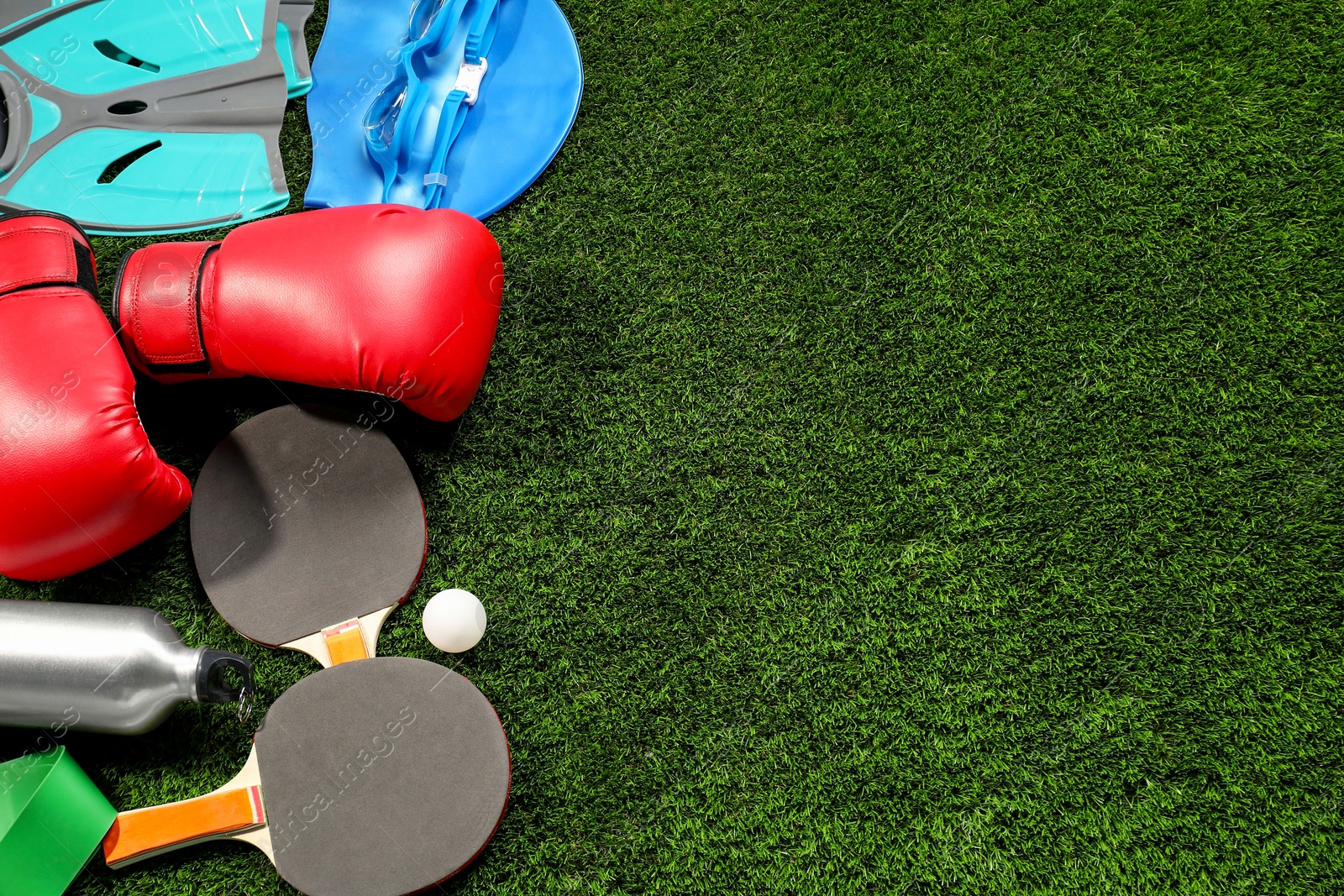 Photo of Different sports equipment on artificial grass, flat lay. Space for text