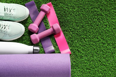 Photo of Different sports equipment on artificial grass, flat lay. Space for text