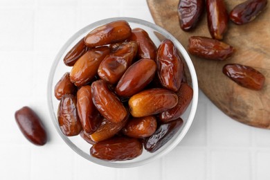 Photo of Tasty dried dates in glass bowl on white table, top view