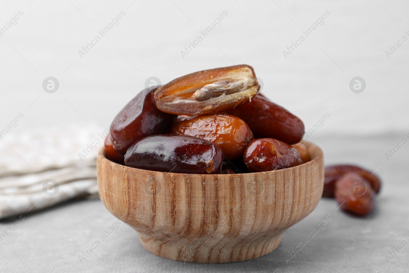 Photo of Tasty dried dates in bowl on light grey table, closeup