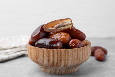 Photo of Tasty dried dates in bowl on light grey table, closeup