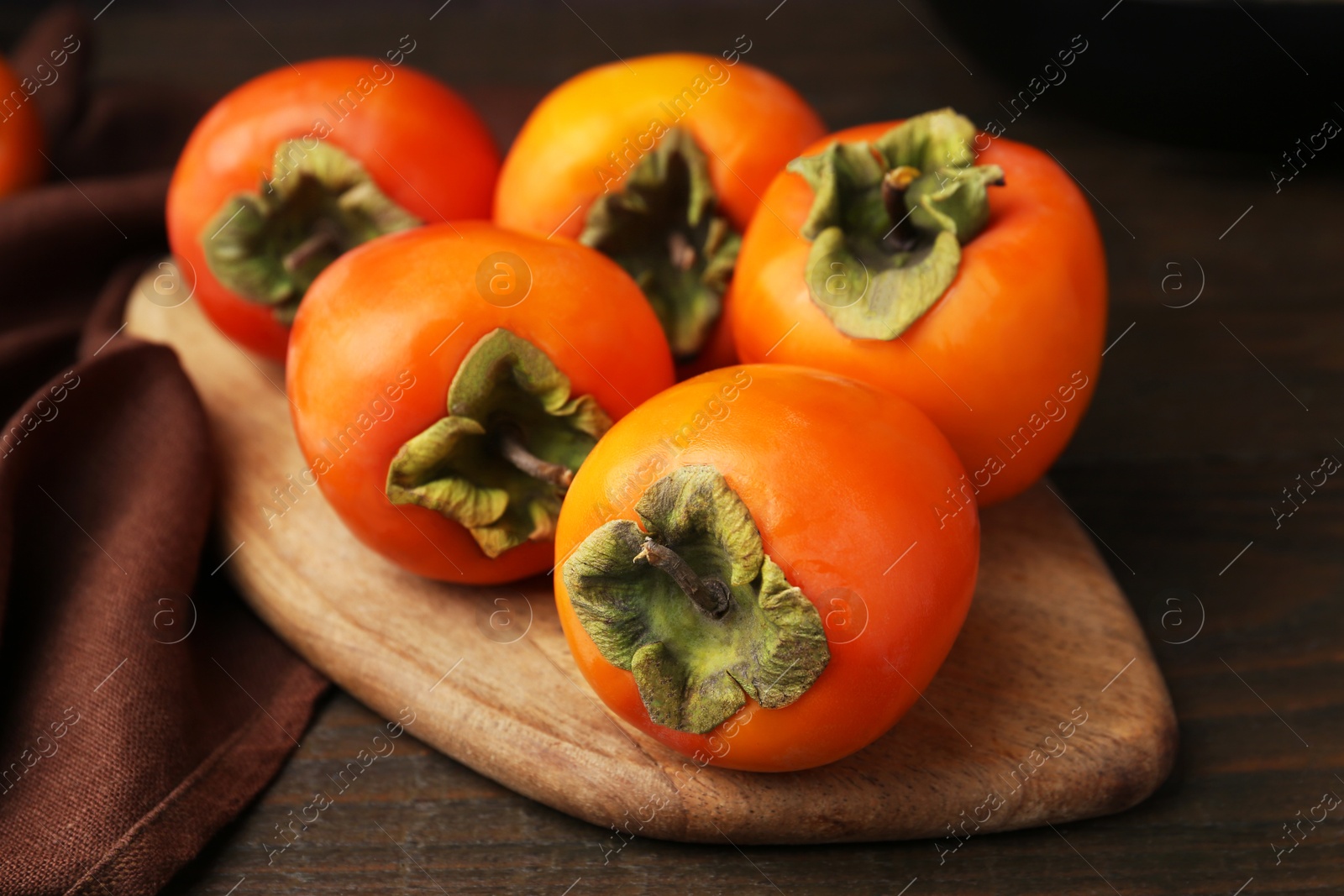 Photo of Delicious fresh juicy persimmons on wooden table, closeup