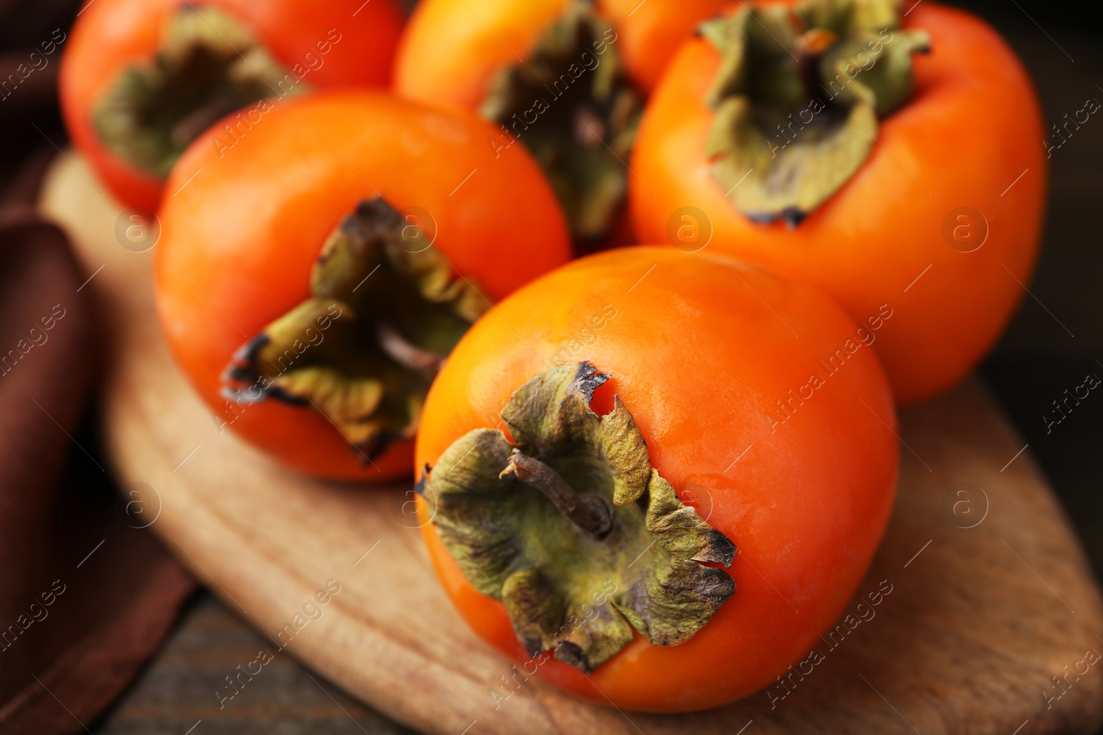 Photo of Delicious fresh juicy persimmons on wooden table, closeup