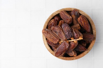 Photo of Tasty dried dates on white tiled table, top view. Space for text