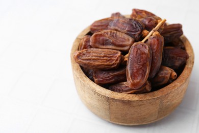 Photo of Tasty dried dates on white tiled table, closeup. Space for text